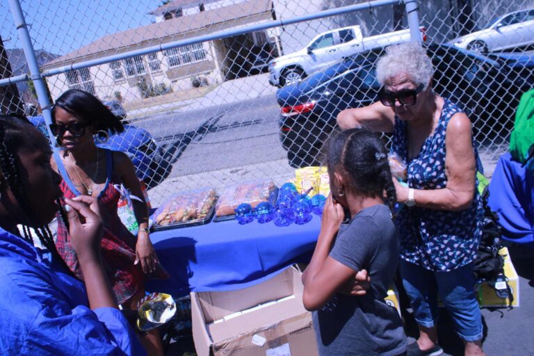 Children standing on food stall with ladies